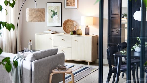 Ett ERSNÄS sideboard med björkeffekt mot en vit vägg med en SÖDERHAMN soffa i beigebrunt med en golvlampa framför.