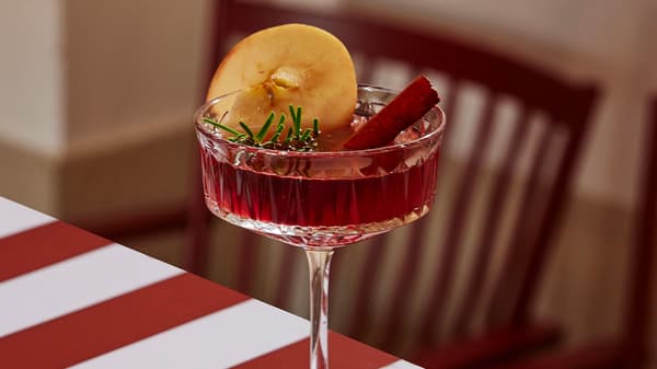 Ett fint champagneglas fyllt med glöggsangria dekorerat med apelsiskiva och kanelstång. 