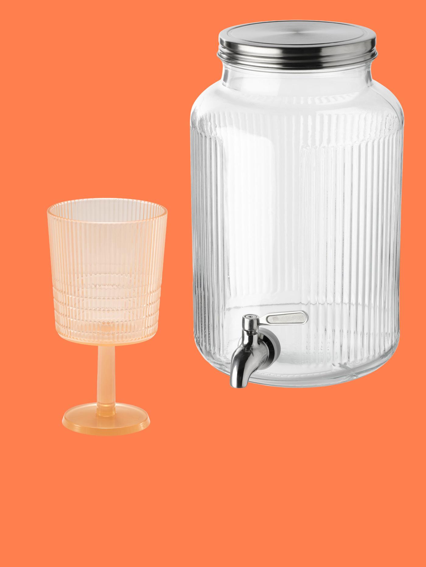 Ett glas på fot och en behållare i glas mot orange bakgrund. 