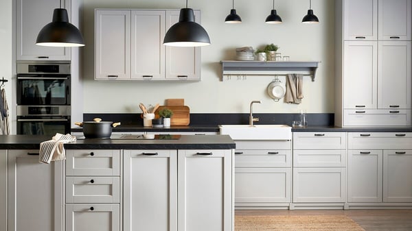 Ett ljusgrått lantligt kök, platsbyggt, med LERHYTTAN köksluckor.