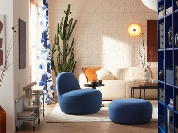 Ett modernt vardagsrum med en vit soffa och en blå fåtölj. 