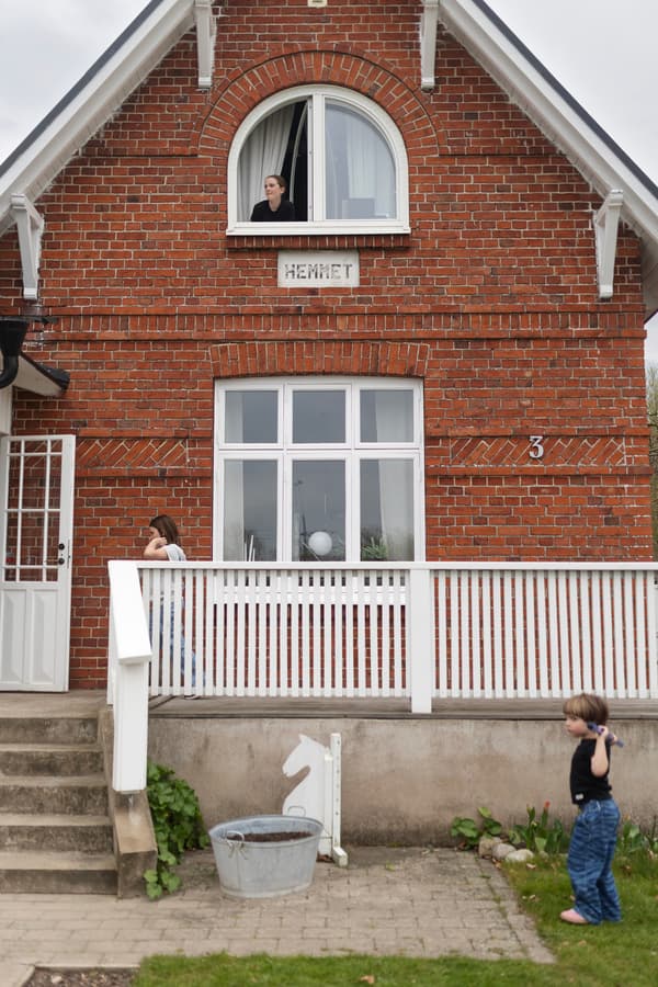 Ett rött tegelhus med ett vitt staket. 
