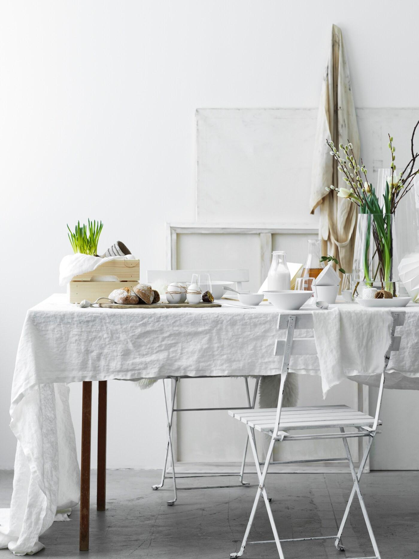 Ett vitt bord med vårblommor i en genomskinlig vas.