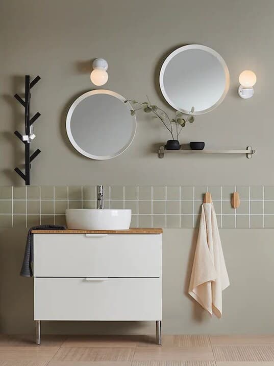 Ett vitt IKEA badrum med två runda speglar på vägen.