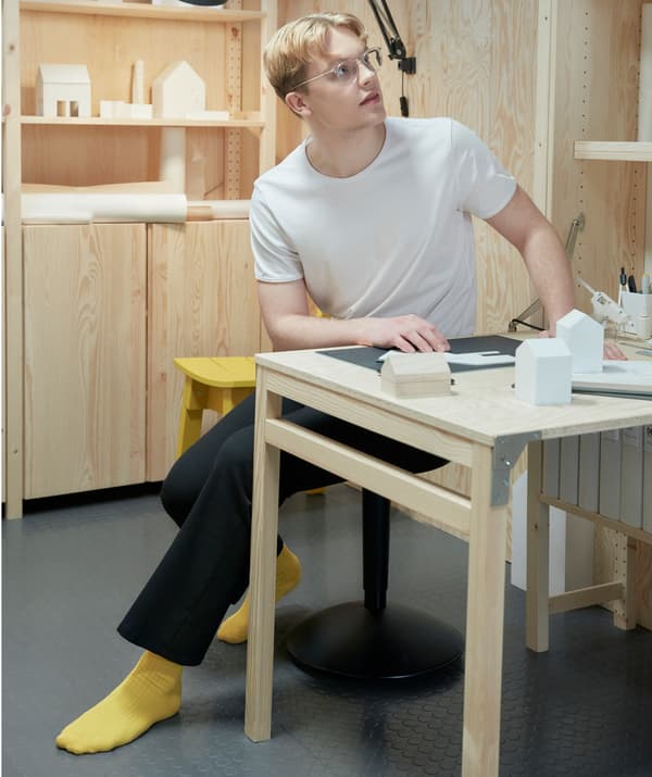Étudiant en pleine réflexion assis à un bureau et travaillant à un projet.