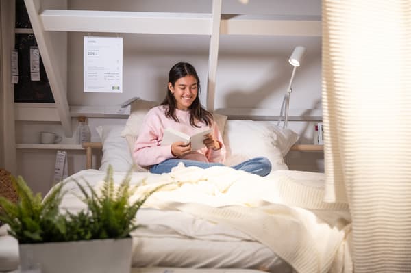 Étudiante assise sur son lit en train de lire un livre