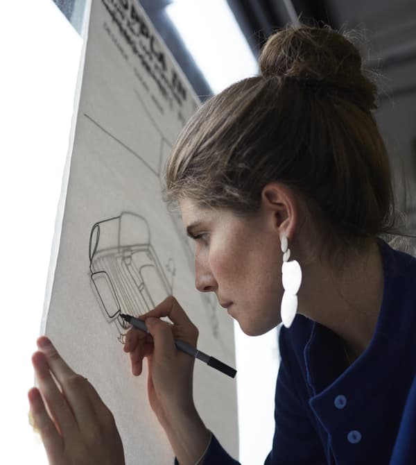 Étudiante en train de tracer des dessins du canapé DELAKTIG sur un caisson lumineux.