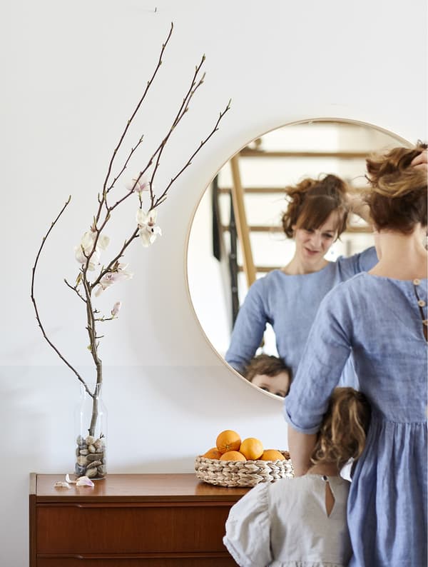Eva and her daughter standing in front of a mirror and sideboard.
