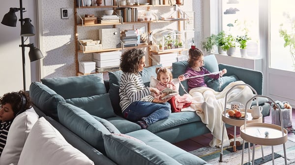 Family sat on  blue corner shaped SÖDERHAMN sofa, engaging in Knitting activities together.