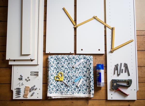 Fabric, pieces of an unassembled BILLY bookcase, and tools laid out on the floor.