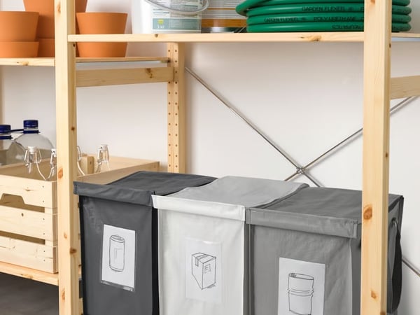 Fabric recycling bins arranged on wooden shelving in a utility space.