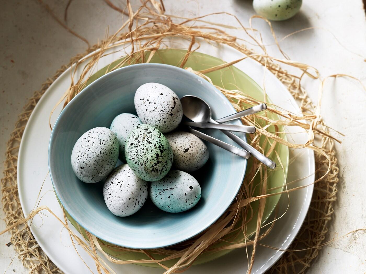 Färgstänkta ägg ligger i en ljusblå skål.