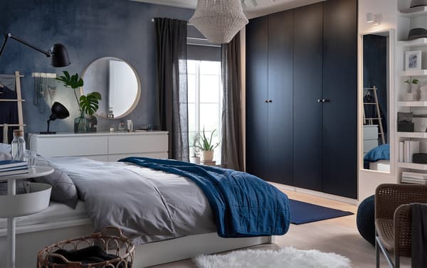 Faites baigner votre chambre à coucher dans une ambiance bleue et apaisante avec les nouvelles portes de garde-robe bleu-noir IKEA PAX HAMNÅS, le pouf bleu foncé SANDARED et le tapis tissé à plat bleu foncé STOCKHOLM.