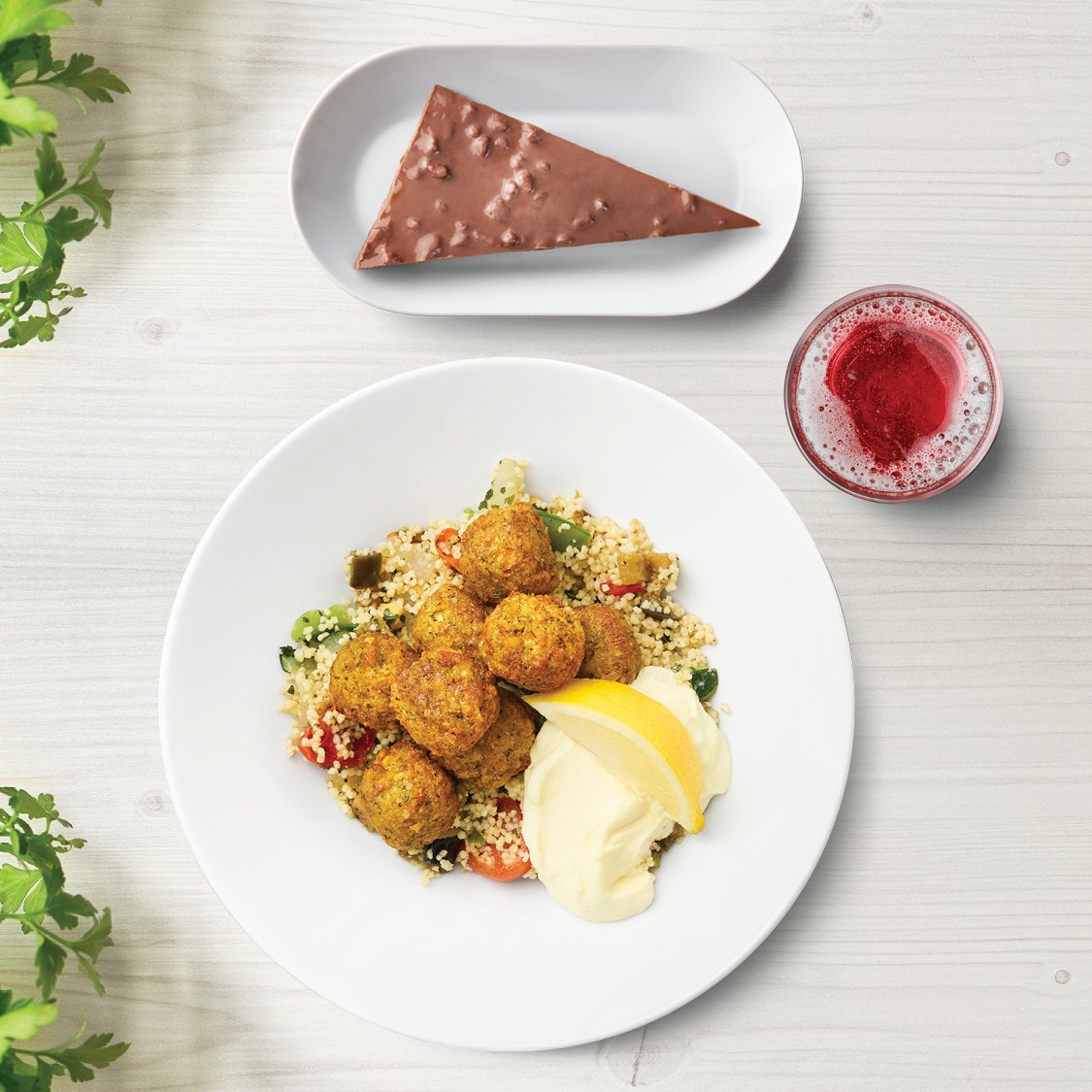 Falafelbullar mit Beilage, einem Stück Daim Torte und einem Schwedenkracherl auf einem Tisch präsentiert