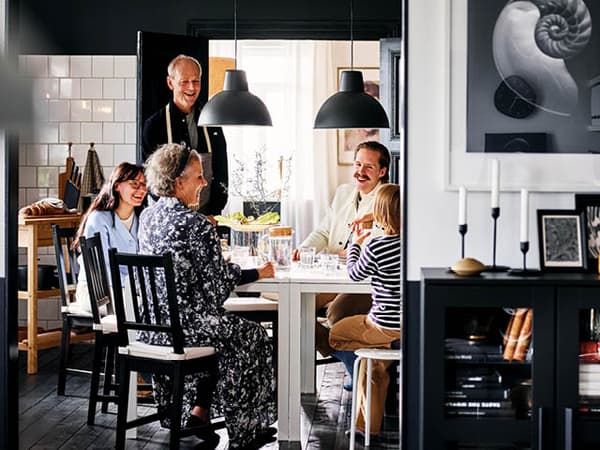 Familj sitter runt matbord i ett kök och konverserar