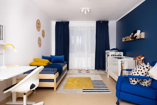 Family room with a baby after interior makeover, blue walls, sofa, and baby area.