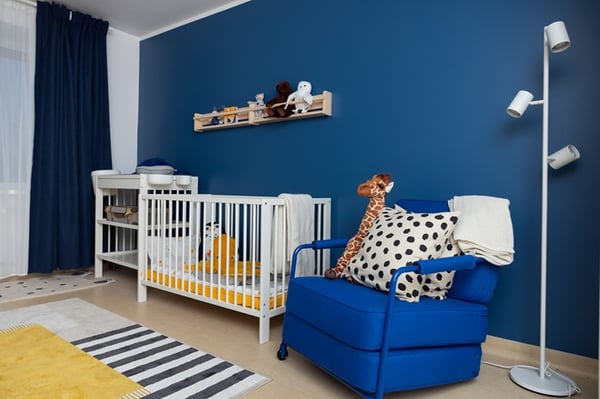 Family room with baby crib, lounge chair, and calm lighting after renovation.