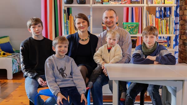 Family with three children sitting in a bright kids room with shelves and toys
