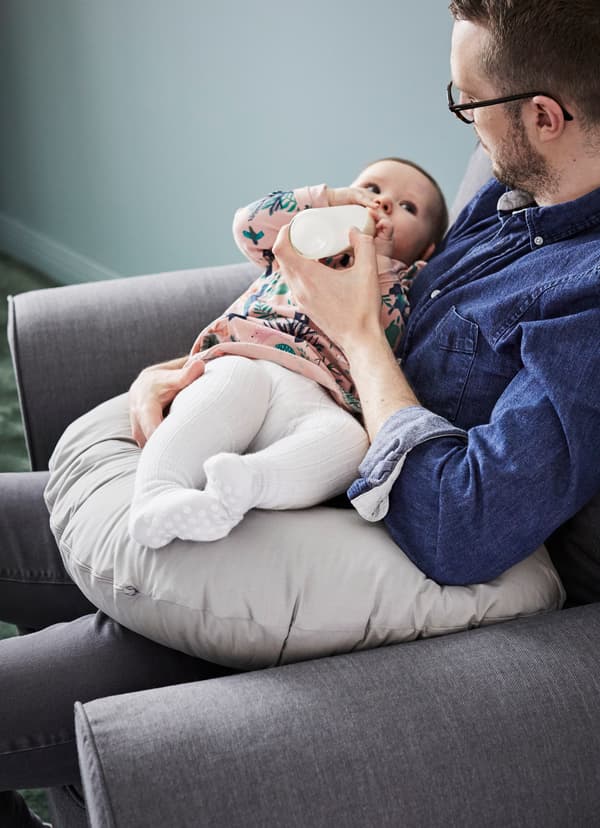 Father bottle-feeding his baby on LEN grey nursing pillow.