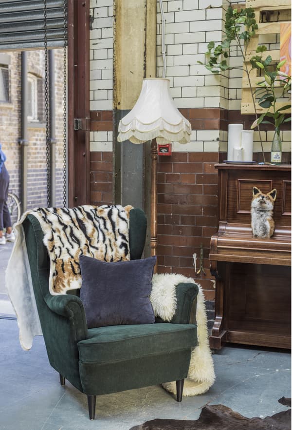 Fauteuil, coussin et plaid dans un espace industriel.