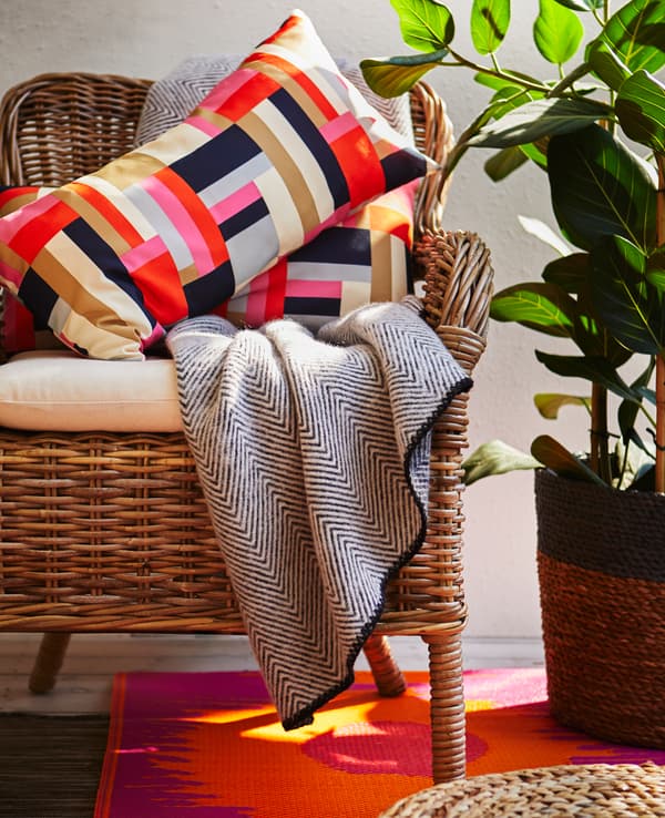 Fauteuil garni d’un coussin d’assise confortable, de coussins et d’un plaid.