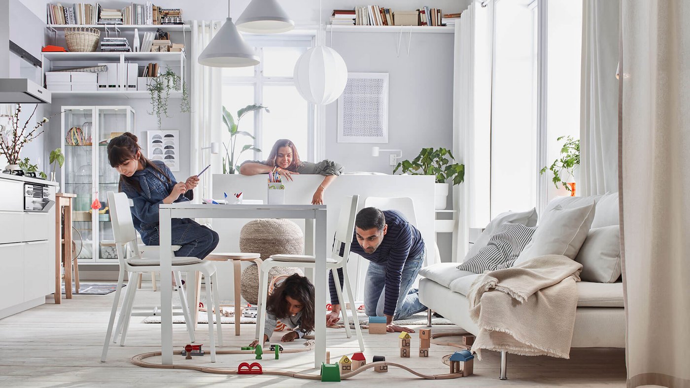 A family in a dining room with white home furnishings and toys.