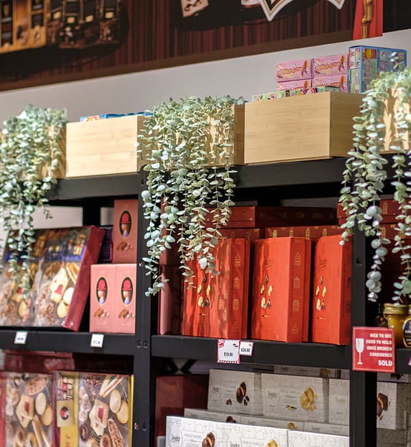 FEJKA artificial potted plants are displayed a BROR shelving unit filled with products.