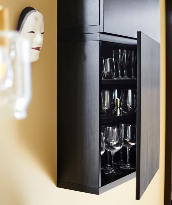 Fekete faliszekrény, nyitott ajtóval, benne üvegáruval.