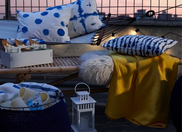 Felfordított üreges puff, textíliákkal és LED gyertyákkal egy dohányzóasztal és egy függőágy mellett, textíliákkal.