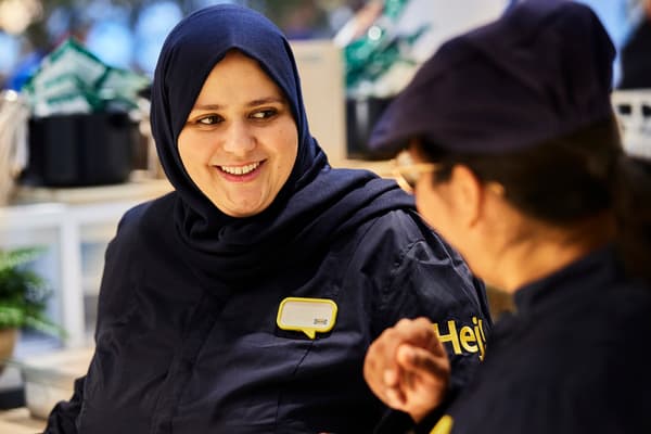 Female coworker wearing headscarf speaks with customer