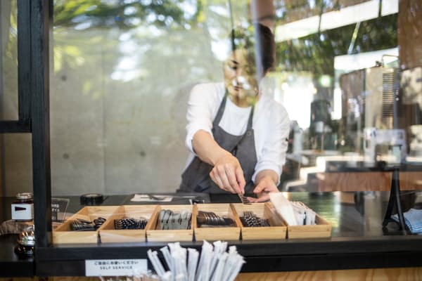 Female worker puts cutlery away at cafe 