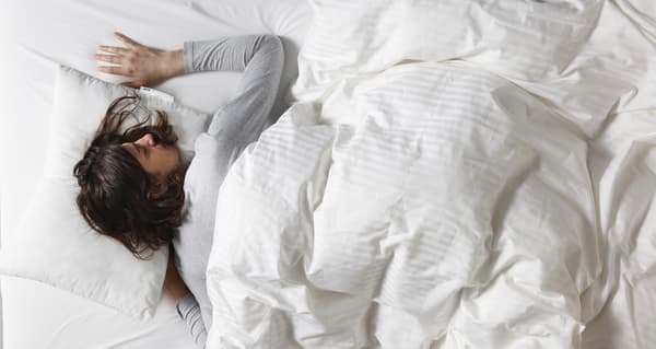 Femme allongée sur le ventre sous la couette