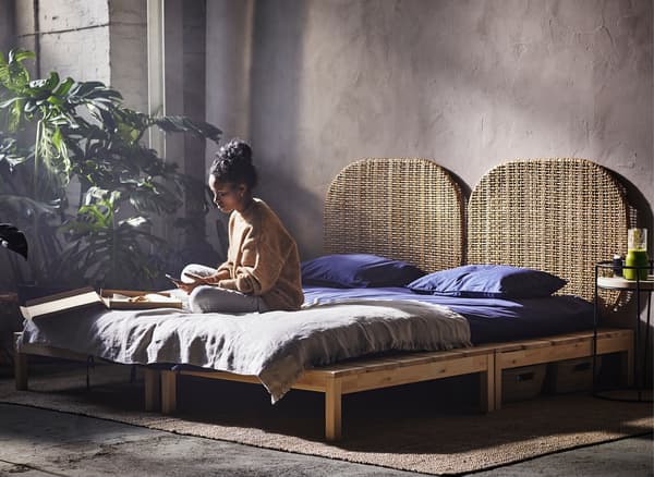 Femme assise jambes croisées sur un lit, dans un entrepôt.