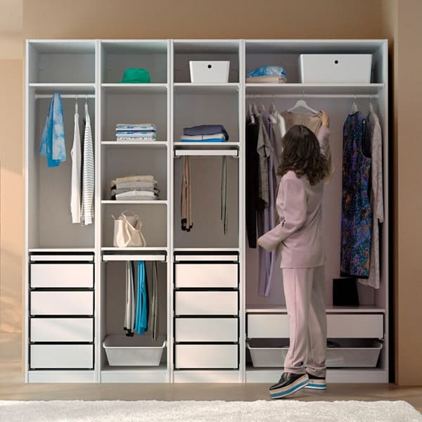 Femme attrapant un ceintre dans une penderie ouverte avec différents rangements intégrés et vêtement pendues