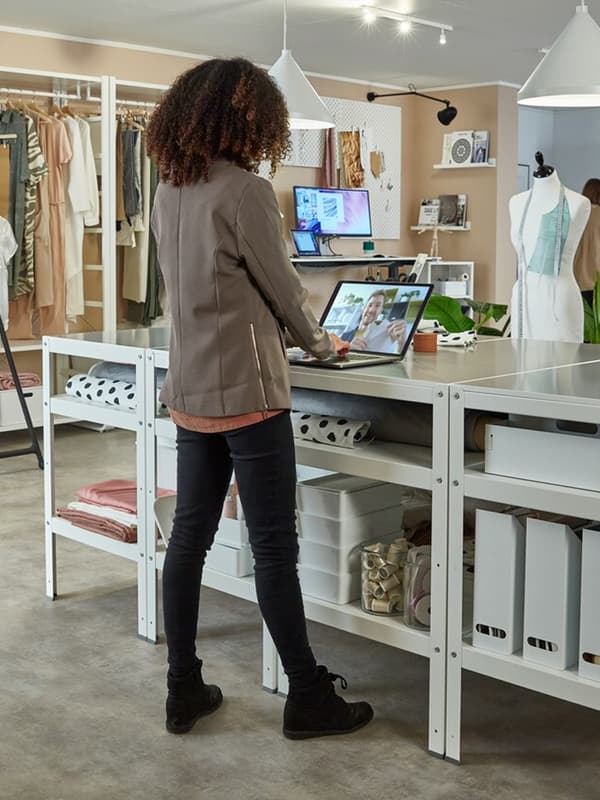 Femme debout dans un open space sur son ordinateur.
