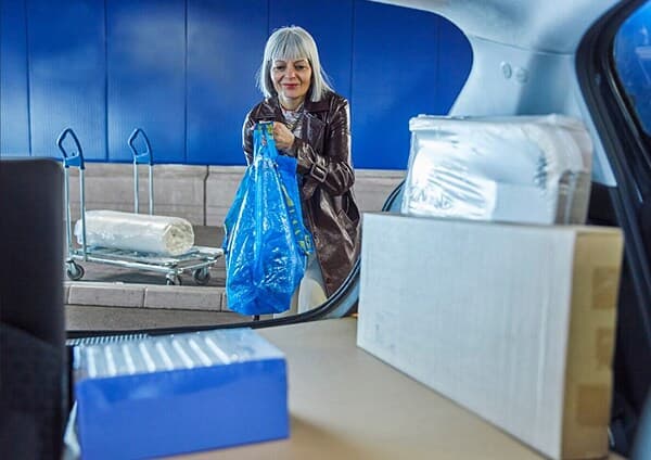 Femme en train de charger des articles dans sa voiture.