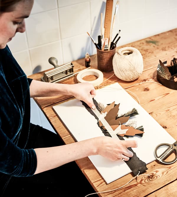 Femme en train de coller des plumes sur un bandeau sur le thème de Thanksgiving.