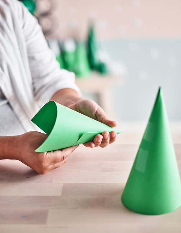 Femme en train de faire des cônes en papier pour les sapins de l'Avent.