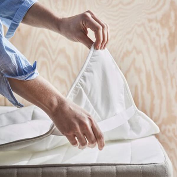 Femme en train de mettre une alèse sur un matelas.
