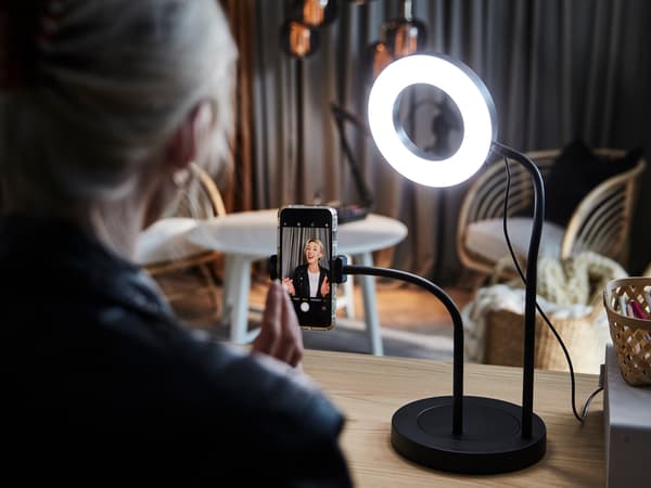 Femme s’enregistrant sur son téléphone devant une bague lumineuse.
