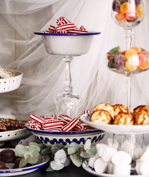 Festive compositions of plates, bowls and wine glasses stacked and glued on top of each other, filled with cookies and candy.