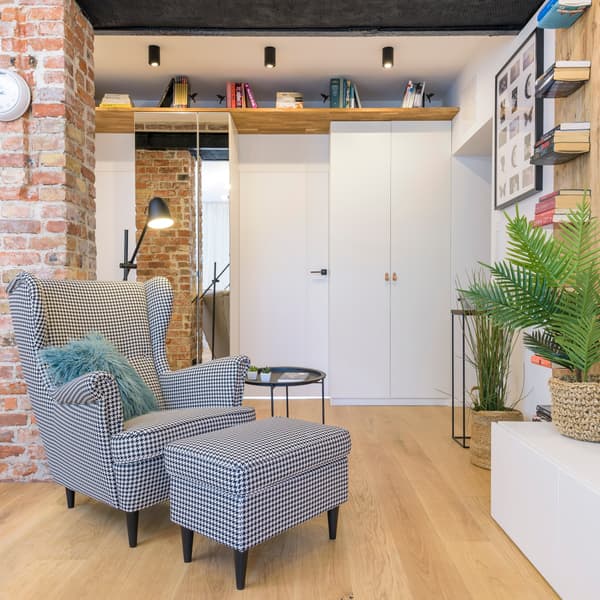 Fetel z podnóżkiem STRANDMON. W tle biała szafa PAX.