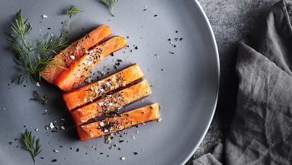 Fette di salmone condite con sale, pepe e aneto su un piatto grigio. Accanto al piatto, un tovagliolo grigio - IKEA
