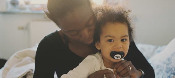 Fillette assise sur les genoux de sa maman dans une pièce ensoleillée.