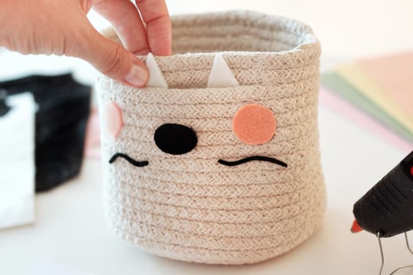 Filzteile werden auf den TJABBIG Korb aufgeklebt, damit ein Fledermausgesicht für den DIY Halloweenkorb entsteht.