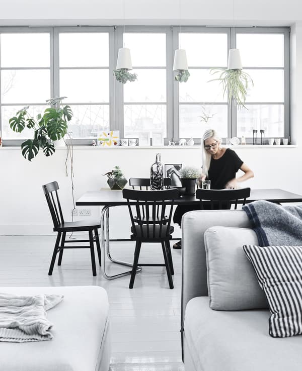 Fiona at her black vintage dining table that sits six people in a shared dining room and living room area.