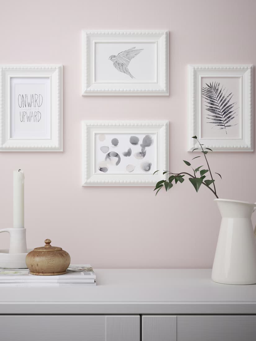 FISKBO white photo frames for 3R or 4R photos in the living room mounted on a pink wall above a storage sideboard cabinet.