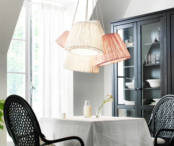 Five fabric lampshades in pink and white fabric hang in a cluster above a two-person dining table.