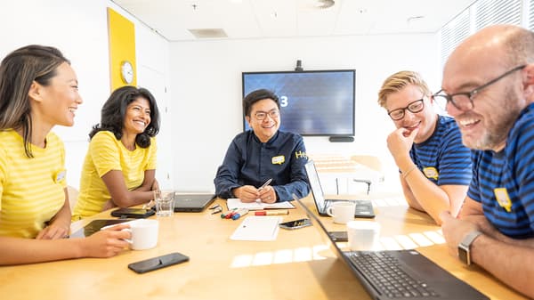 Five IKEA co-workers are sitting in a meeting room, having a meeting.