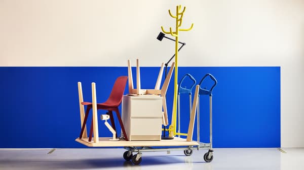 Flatbed cart with IKEA furniture pieces including a red chair, white drawer unit, and yellow coat rack.